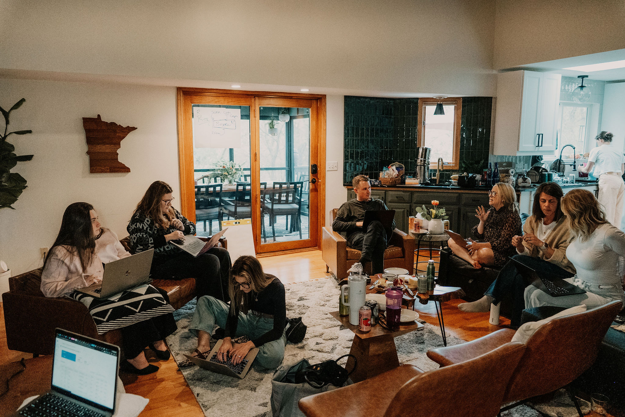 Three of the team curled on a couch with laptops, a dog at their feet