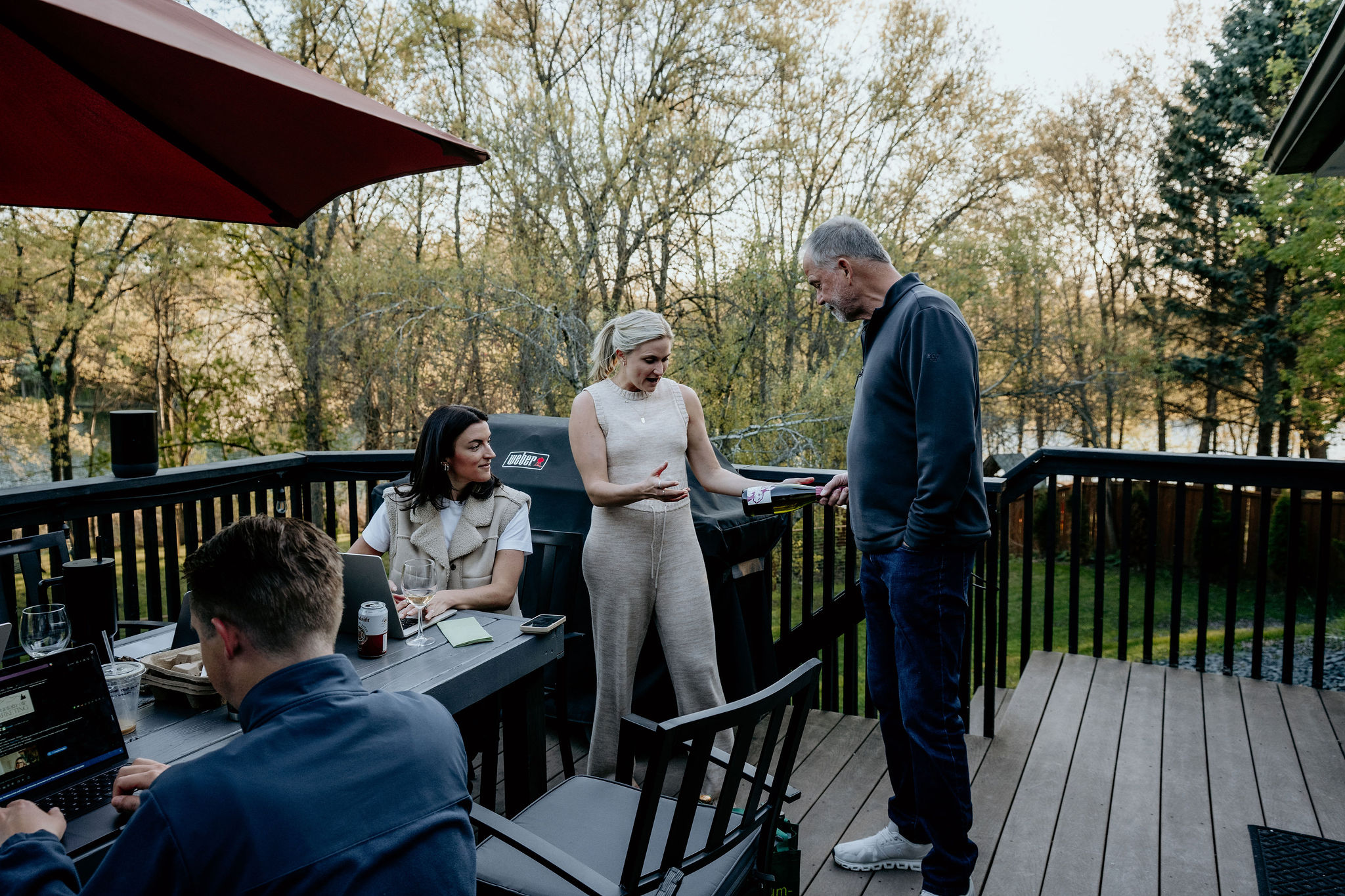 The team gathered on the deck at golden hour, wine being poured at the table